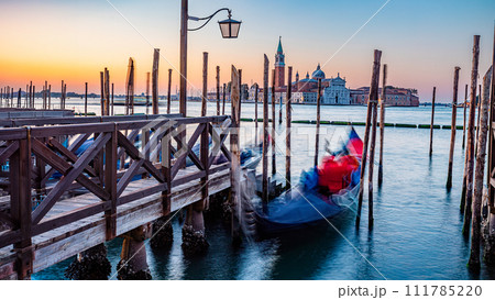 Blurred Gondolas at Saint Mark Square pier with San Giorgio di Maggiore Church during sunrise, Venice 111785220