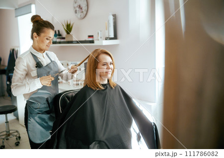 woman hairdresser in modern hair studio cutting hair 111786082
