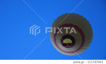 Bottom view of balloon flight with bright flame against blue sky. Unusual angle. Ballooning in Cappadocia. Close-up view. 111787041