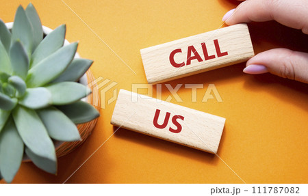 Call Us symbol. Wooden blocks with words Call Us. Beautiful green background with succulent plant. Businessman hand. Business and Call Us concept. Copy space. Call Us symbol. Wooden blocks with words Call Us. Beautiful green background with succulent plant. Businessman hand. Business and Call Us concept. Copy space. 111787082