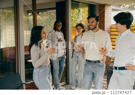 Group of friends enjoying in conversation and drinking wine during holiday party at home terrace 111787427