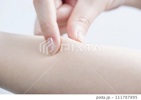 皮ふを摘む女性の指先1 111787895