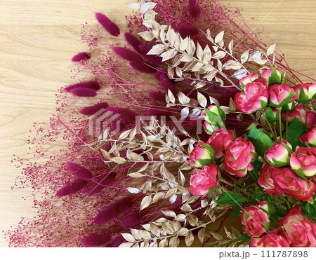 ウッド背景のゴールド、レッド、ピンク、パープル系フラワーアレンジメント 111787898
