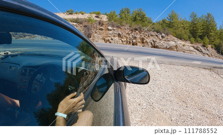 A car on a winding mountain road. The camera is mounted on the side window of the car. Part of the interior and the driver's hands can be seen. 111788552