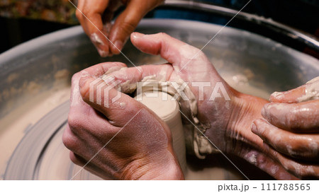 A potter's hands transform a lump of white clay into a beautiful piece of pottery in close-up. An open class is in progress. The potter at work in the pottery workshop. 111788565