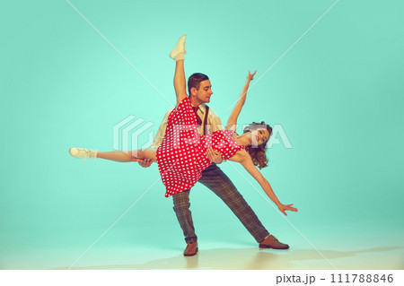 Swing dancers radiating happiness while performing energetic dance moves in motion against gradient mint background. Swing dancers radiating happiness while performing energetic dance moves in motion against gradient mint background. 111788846