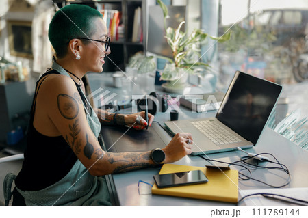 Woman designer uses graphics tablet and laptop for retouching photos or digital drawing in workshop 111789144