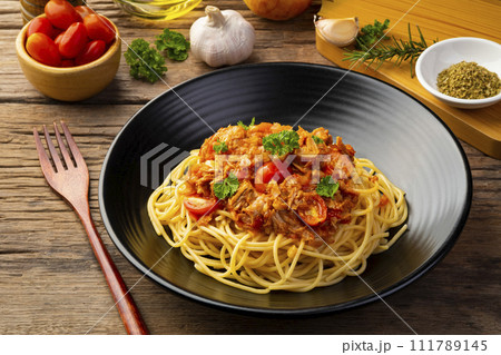 Spaghetti with canned tuna fish in tomato sauce, pasta with a meat based bolognese tomatoes,served in black plate 111789145