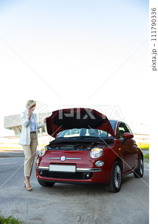 Attractive businesswoman calling to car service for repairing her broken automobile Attractive businesswoman calling to car service for repairing her broken automobile 111790336
