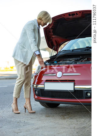Woman standing near broken down car with popped up hood having trouble with vehicle Woman standing near broken down car with popped up hood having trouble with vehicle 111790337