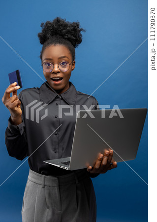 African american business woman with a credit card and a laptop in hands African american business woman with a credit card and a laptop in hands 111790370