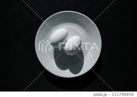 Breakfast - two chicken eggs on a plate with contrasting shadows, black and white image. Breakfast - two chicken eggs on a plate with contrasting shadows, black and white image. 111790958