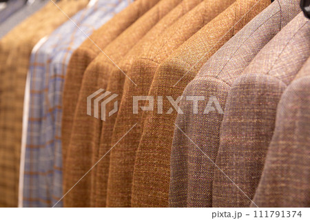 A row of men's suits, jackets hanging on a rack for display. 111791374