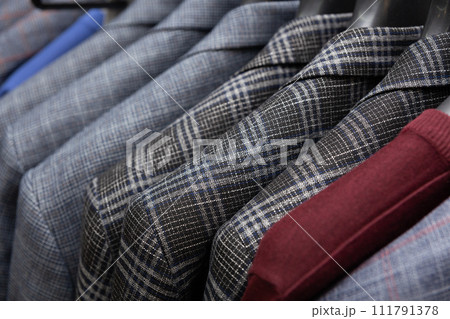 A row of men's suits, jackets hanging on a rack for display. A row of men's suits, jackets hanging on a rack for display. 111791378