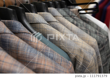 A row of men's suits, jackets hanging on a rack for display. A row of men's suits, jackets hanging on a rack for display. 111791379