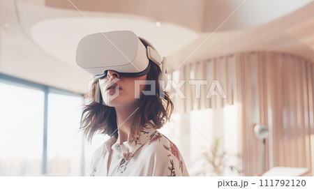 Woman of European appearance, in casual clothes, in a modern room, wearing a white VR virtual reality headset. daylight 111792120