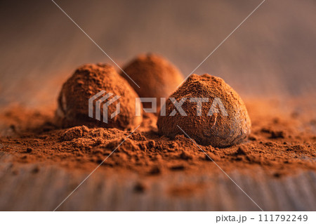 Chocolate truffles covered with cocoa powder on wooden table. Chocolate truffles covered with cocoa powder on wooden table. 111792249