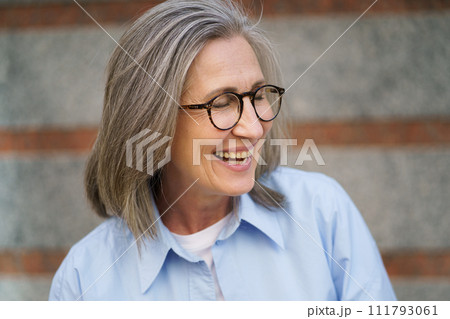 A happy older woman with glasses wearing a blue shirt. A happy older woman with glasses wearing a blue shirt. 111793061