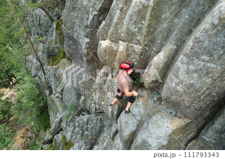 Strong male climber climbing steep wall of rocky mountain. Sportsman overcoming difficult route. Engaging in extreme sports hobby concept. Strong male climber climbing steep wall of rocky mountain. Sportsman overcoming difficult route. Engaging in extreme sports hobby concept. 111793343