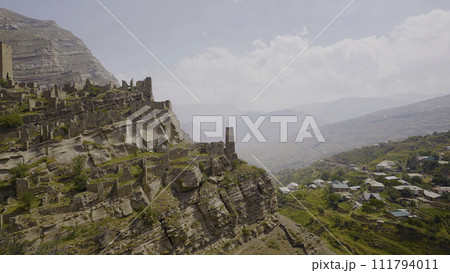 Ruins of ancient city on rocks on sunny day. Action. Stone city on rock in mountains. Historical stone town on rock above mountain valley Ruins of ancient city on rocks on sunny day. Action. Stone city on rock in mountains. Historical stone town on rock above mountain valley 111794011