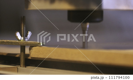 Close-up of wood cutting machine controlled by computer while he is carving wood. Action. CNC milling machine carving a wooden part blank. 111794100