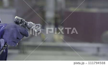 Arm hand holding industrial size spray gun used for industrial painting and coating. Male hand holding paint spray, closeup 111794508