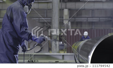 Male holding spray gun and painted steel. Man paints pipe atomizer Male holding spray gun and painted steel. Man paints pipe atomizer 111794542