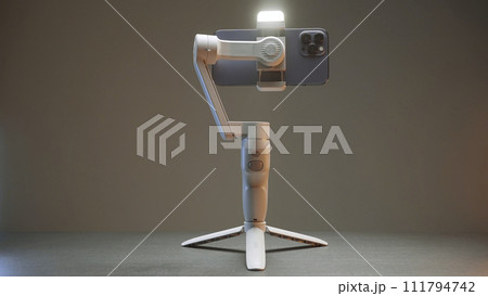 Professional tripod for phone. Action. Assembly model of tripod for professional shooting on phone. White tripod of new model on isolated background Professional tripod for phone. Action. Assembly model of tripod for professional shooting on phone. White tripod of new model on isolated background 111794742