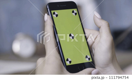 Chroma key screen for placement of your own content. Stock footage. Woman hands with perfect manicure holding smartphone and sliding on the chroma key green screen. Chroma key screen for placement of your own content. Stock footage. Woman hands with perfect manicure holding smartphone and sliding on the chroma key green screen. 111794754