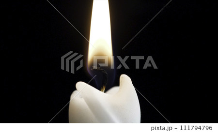 Close up detail of white wax lit candle flame and wick on isolated black background. andle lights macro. closeup of burning candle isolated on black background one flame at night macro brightly in 111794796