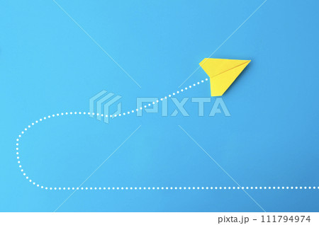 Top view of yellow paper airplane making a U turn on blue background Top view of yellow paper airplane making a U turn on blue background 111794974