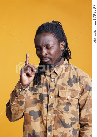 Concentrated man brainstorming ideas to find solution, taking thoughts into consideration while posing over yellow background in studio. Uncertain young adult contemplating about serious problem. 111795397