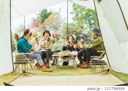 秋冬のキャンプ場で仲間と一緒にビールを飲んでパーティーするアジア人の男女（グループキャンプ） 111796884