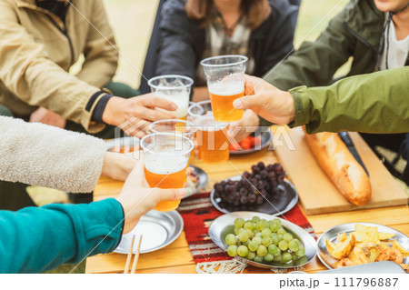 秋冬のキャンプ場で仲間と一緒にビールを飲んでパーティーする男女の手元 秋冬のキャンプ場で仲間と一緒にビールを飲んでパーティーする男女の手元 111796887