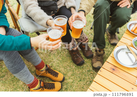 秋冬のキャンプ場で仲間と一緒にビールを飲んでパーティーするアジア人の男女 111796891