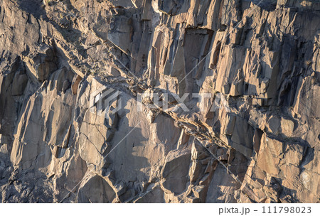 Crumbling rock cliff wall texture with cuts and shadows of The granite rock. Crumbling rock cliff wall texture with cuts and shadows of The granite rock. 111798023