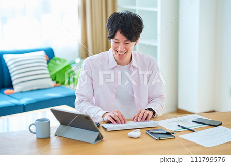 部屋でパソコンの操作をする若い男性 111799576