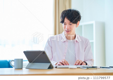 部屋でパソコンの操作をする若い男性 部屋でパソコンの操作をする若い男性 111799577