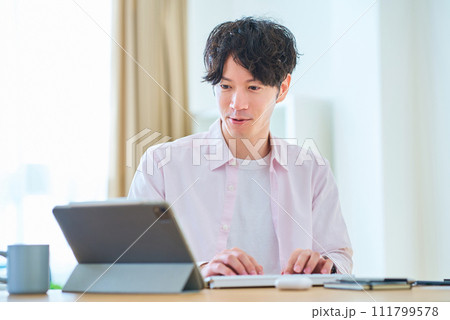 部屋でパソコンの操作をする若い男性 111799578