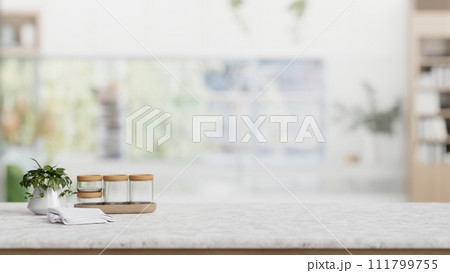 Seasoning bottle, a potted plant, and empty space on a tabletop in a modern white kitchen. 111799755