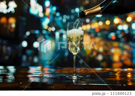 Pouring Champagne into the Champagne glass on the wooden table against blur night life background 111800123