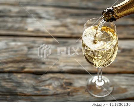 Pouring Champagne into the glass from top view on the wooden table. Pouring Champagne into the glass from top view on the wooden table. 111800130