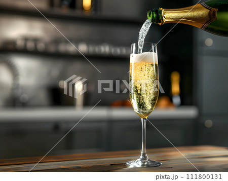 Pouring Champagne into the Champagne glass on the wooden table against blur room background 111800131