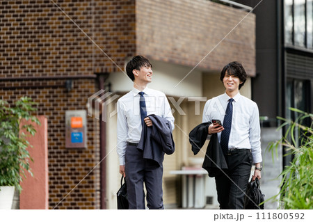 屋外で手帳を広げ真剣な表情で内容を確認する20代のスーツの男性1人 屋外で手帳を広げ真剣な表情で内容を確認する20代のスーツの男性1人 111800592