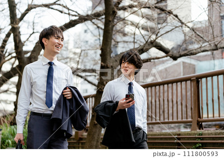 屋外で手帳を広げ真剣な表情で内容を確認する20代のスーツの男性1人 111800593