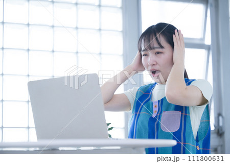 パソコンの前で疲れた表情の女性　保育士や介護士の残業のイメージ 111800631