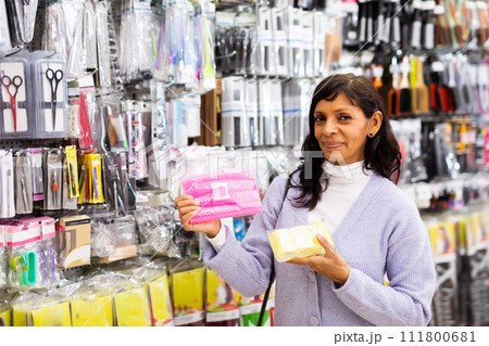 Smiling latina choosing hair rollers in store 111800681