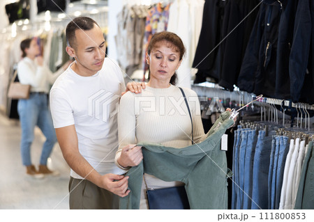 Young couple choosing casual pants in clothing store Young couple choosing casual pants in clothing store 111800853