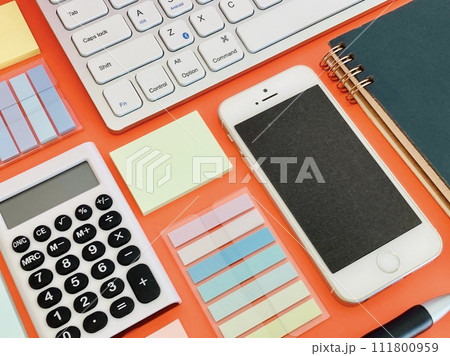 赤いテーブルに並べられたスマホ・PCと文房具 111800959