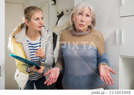 Young female social worker conducts a survey with an elderly woman Young female social worker conducts a survey with an elderly woman 111801008